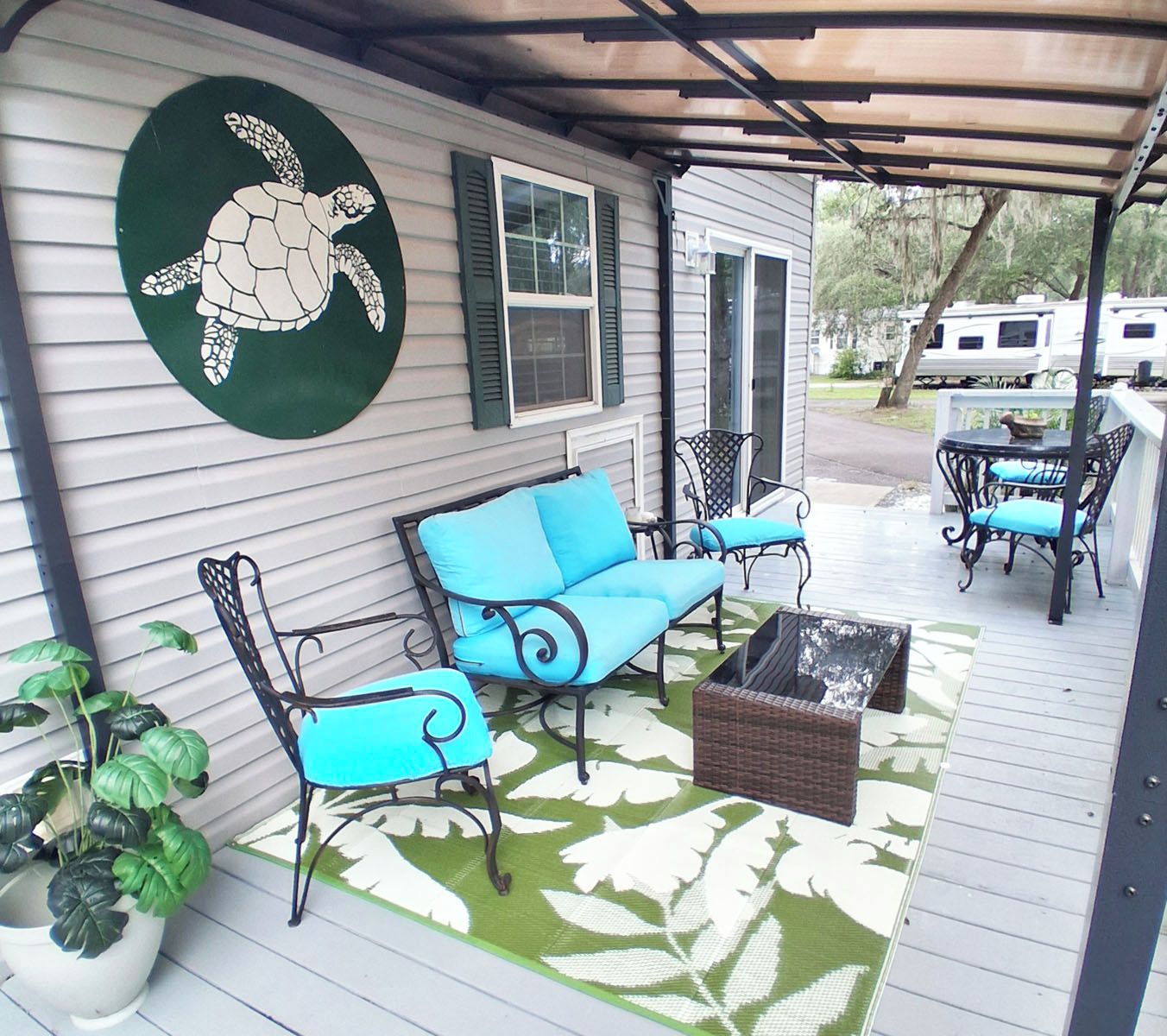 A covered porch with outdoor furniture, a turtle mural, and a view of a vehicle in the background.