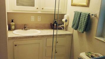 Un baño con inodoro, lavabo, tocador y espejo con luces.
