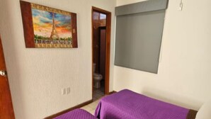 Ein Zimmer mit zwei Betten, einem Bild des Eiffelturms, einer Klimaanlage und einem Fenster.