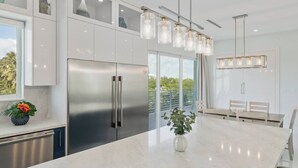 A modern kitchen with a large island, stainless steel appliances, and pendant lighting. - Marathon Sombrero Beach  5 min to Beach, Pool, 70' Dock, Elevator (Marathon)