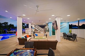 Uma ampla área de estar ao ar livre com piscina, assentos confortáveis e escadaria para um nível superior.