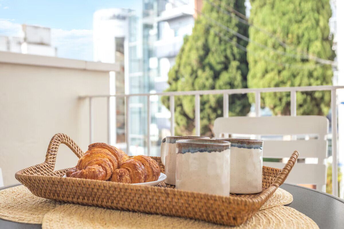 Ein Korbbasket mit Croissants und zwei Keramiktassen auf einem Tisch.