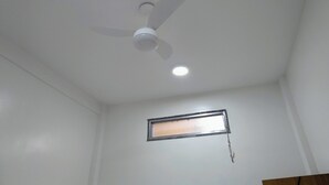 A ceiling fan with a light fixture and a small window with a metal frame. - POUSADA RENASCER MAGE  (Mage)