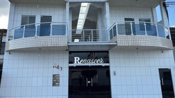A modern building with a tiled facade, a central entrance with a glass door, and balconies with railings. - POUSADA RENASCER MAGE  (Mage)