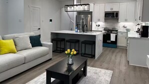 A modern kitchen with white cabinets, a stainless steel refrigerator, and a built-in oven. - Luxury home Near NRG, Med Center, Downtown (Houston)