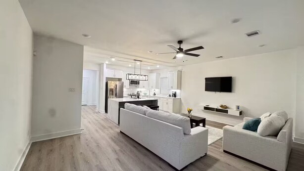 A modern living room with a sofa, a coffee table, and a TV mounted on the wall. - Luxury home Near NRG, Med Center, Downtown (Houston)