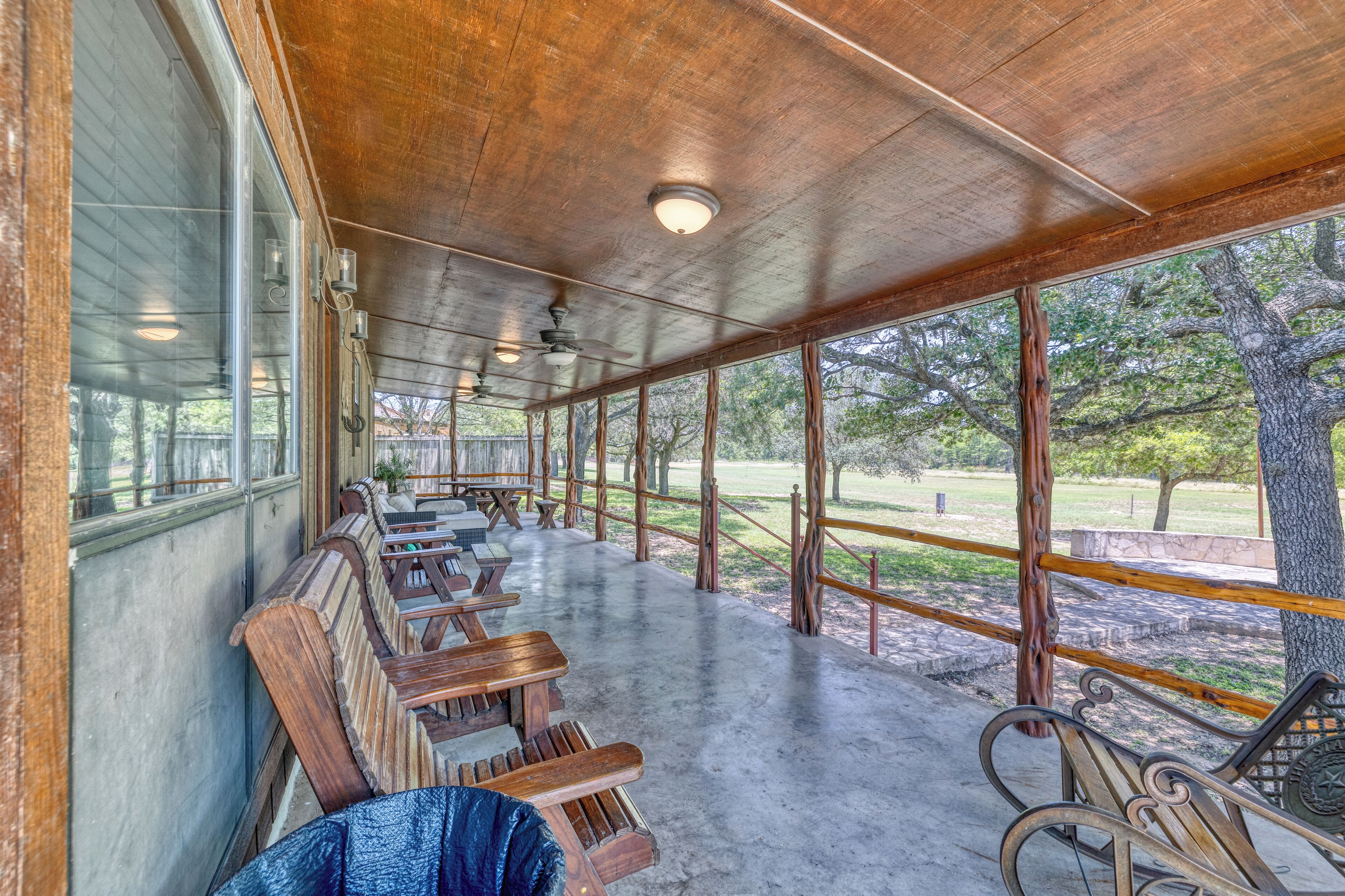 A covered outdoor seating area with wooden benches and a view of a park.