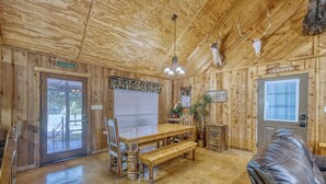A wooden interior with a dining table, benches, and a leather chair.