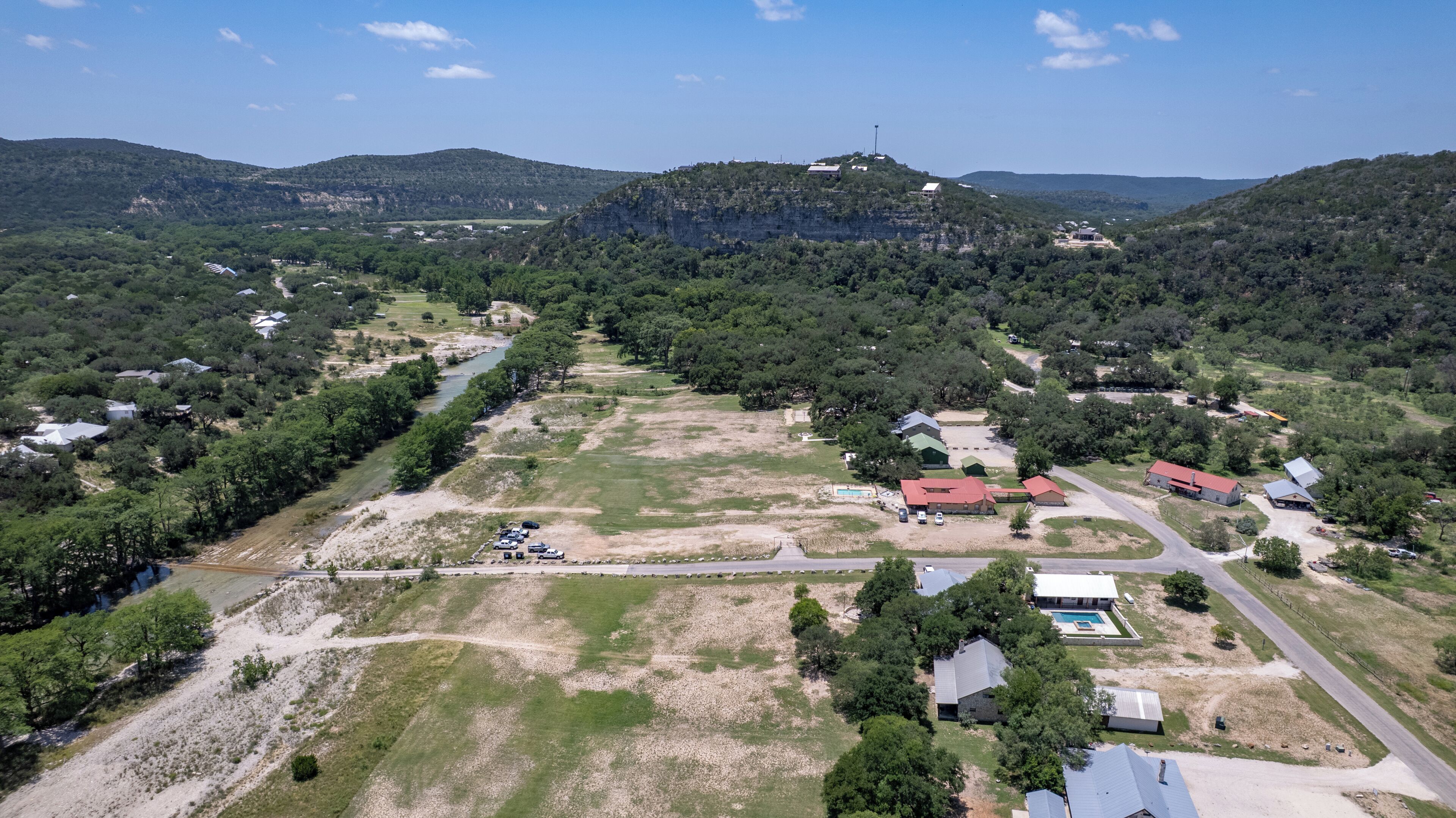 An aerial view of a residential area with houses, a swimming pool, and a road.