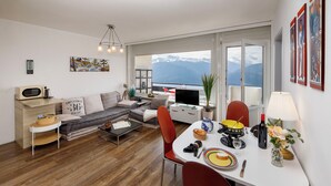 Una sala de estar moderna con sofá, mesa de comedor y vistas a las montañas.