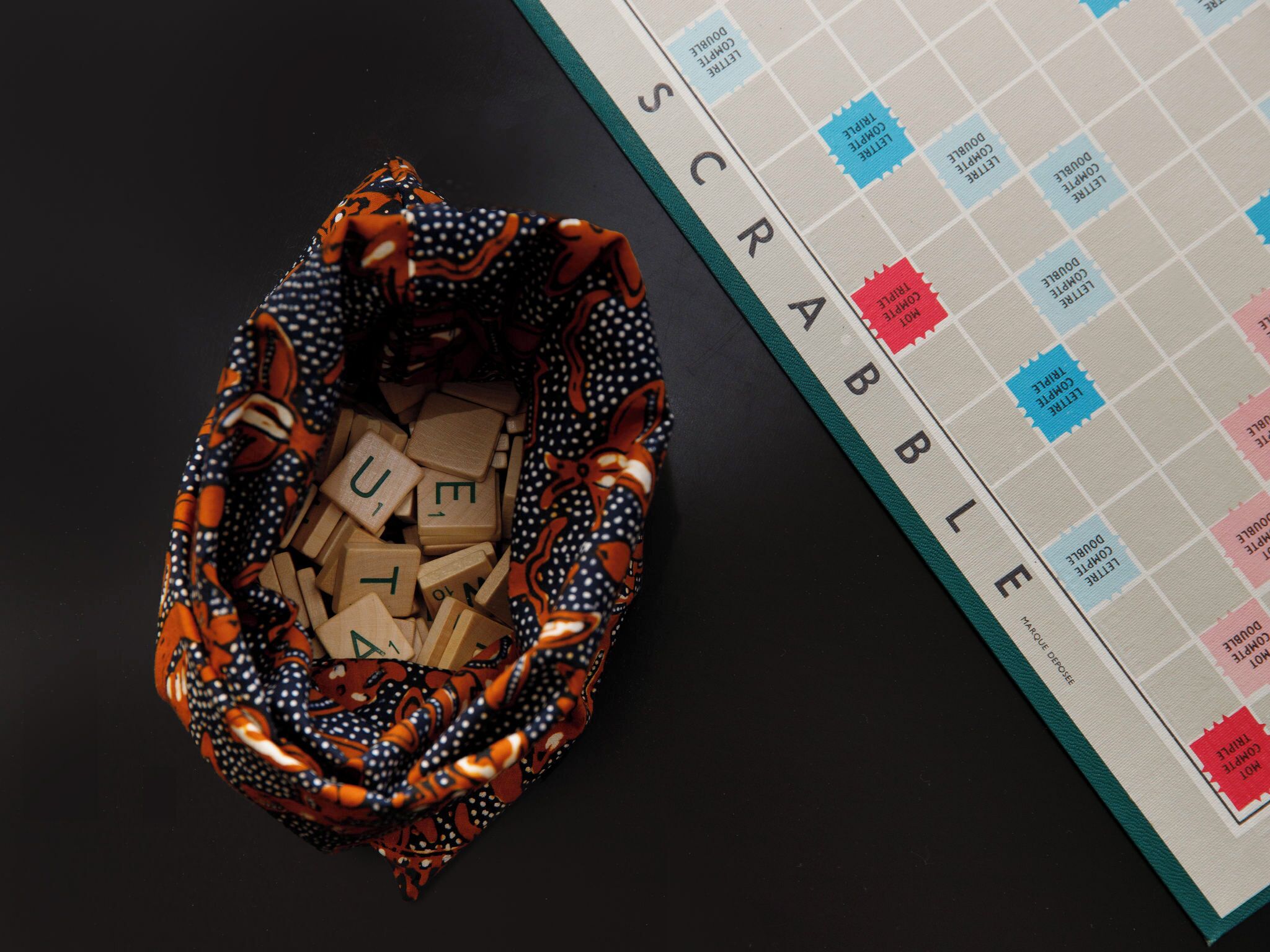 Un juego de Scrabble junto a una bolsa con fichas de letras.