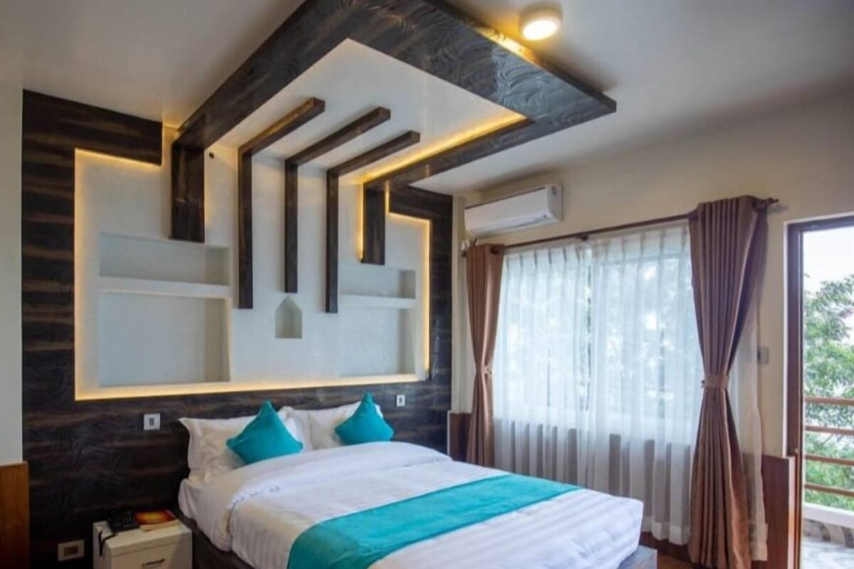 A modern hotel room with a large bed, a built-in headboard, and a view of the outdoors.
