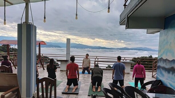 A group of people exercising outdoors with a scenic mountain view in the background.