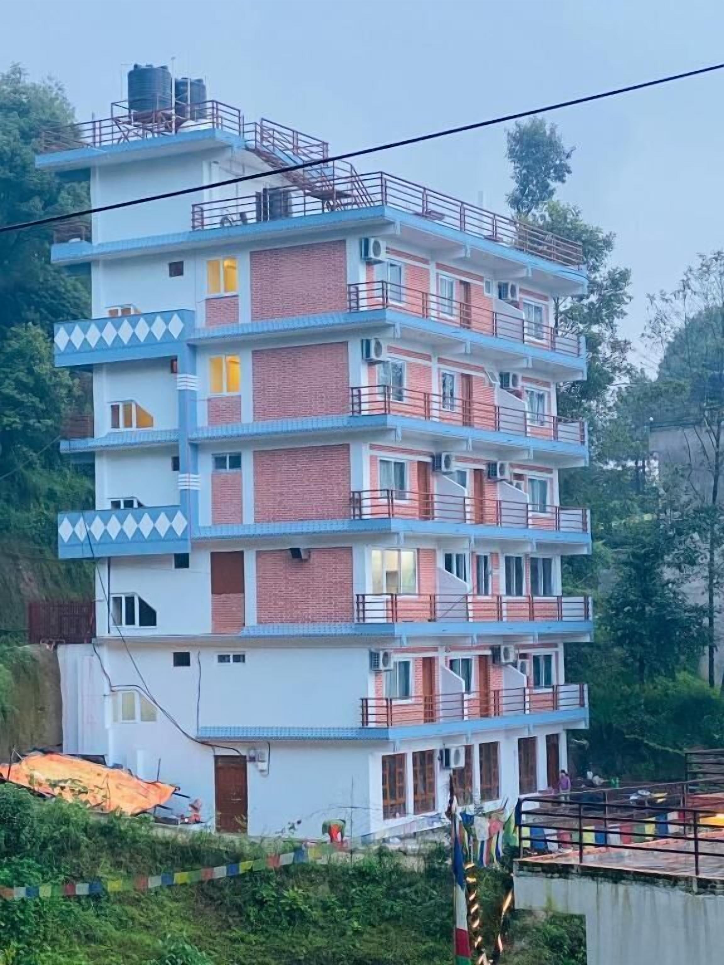 A multi-story building with balconies, air conditioning units, and a water tank on the roof.