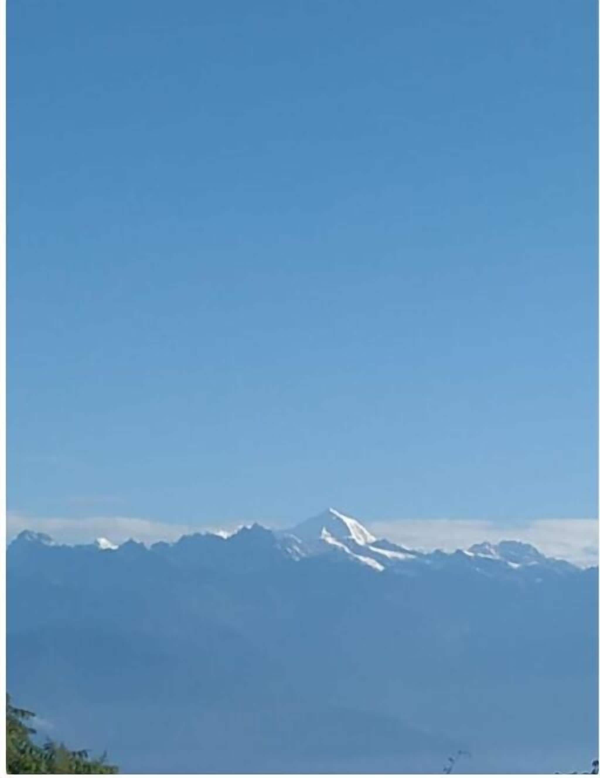 A mountain range with snow-capped peaks under a clear blue sky.