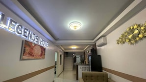 Vestíbulo de hotel con un cartel que dice "LEGENDS HOTEL", piso de mármol, un sofá y un elemento decorativo en la pared.