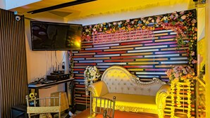 Una habitación con un sofá, un televisor montado en la pared y un adorno floral.