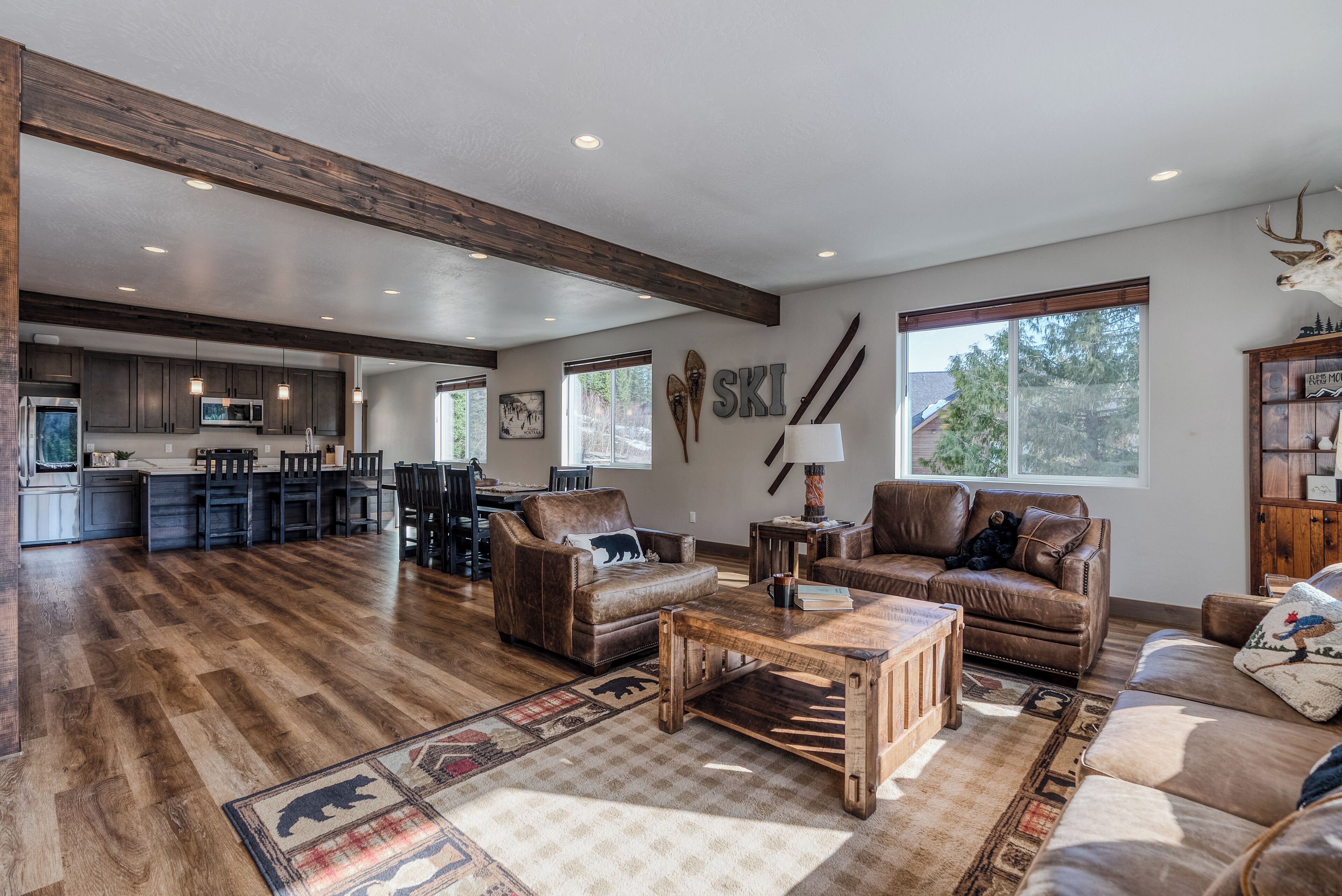 Un vaste espace de vie doté d’un plancher en bois, de canapés en cuir, d’une table basse et d’un tapis à motifs animaliers.