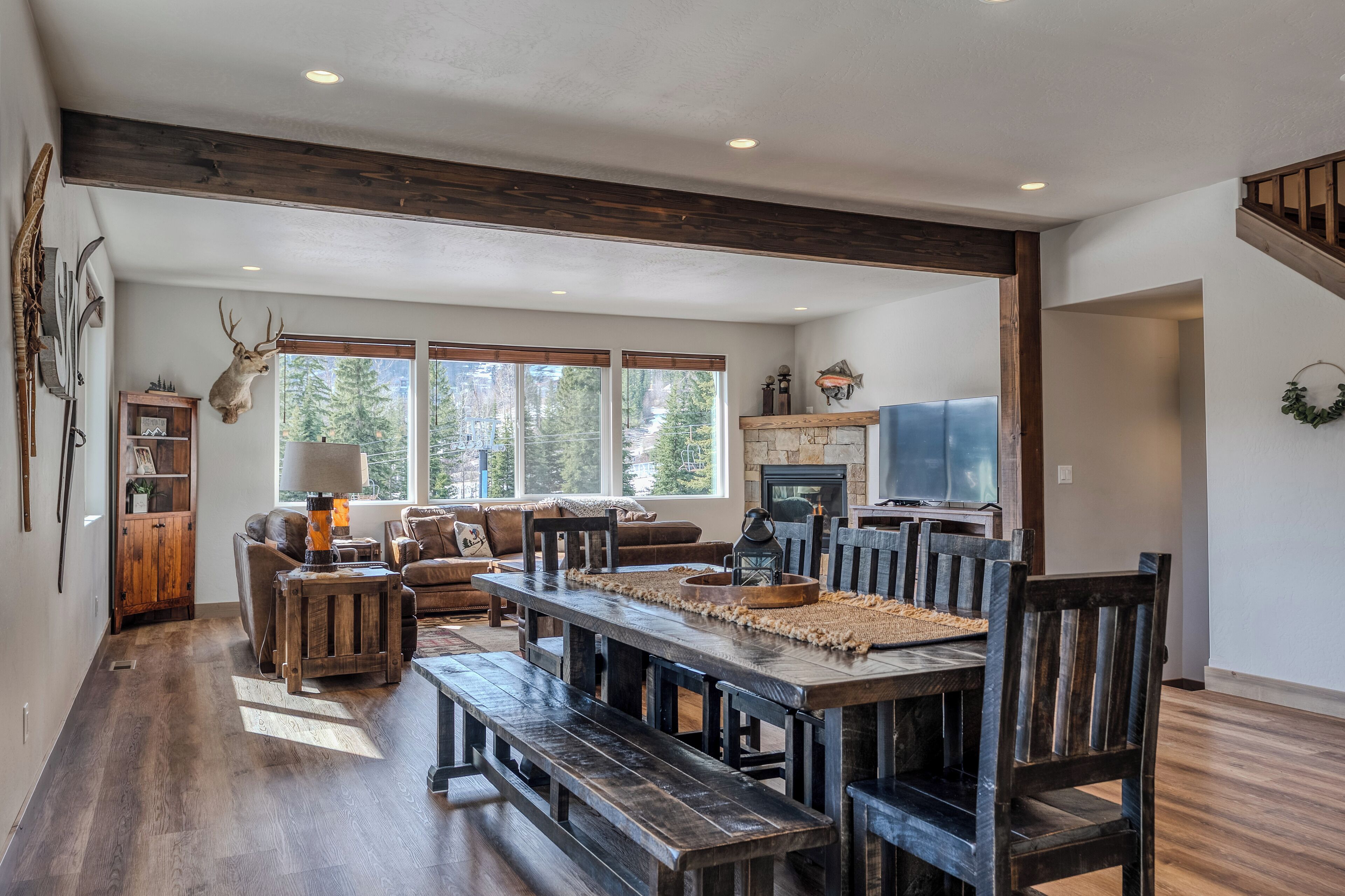 Un salon spacieux avec une grande table à manger en bois, des bancs en bois foncé et une cheminée en pierre.