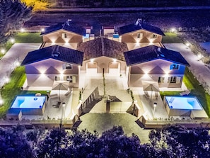 Ett symmetriskt hus med flera våningar, en central innergård, flera balkonger och en swimmingpool.