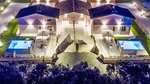 A symmetrical, multi-story house with a central courtyard, two swimming pools, and a well-lit exterior. - Borgo il Vallin delle Conche by Interhome (Cecina)