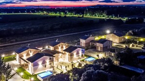 Un complejo residencial con varias casas, una piscina y un camino de entrada bien iluminado.