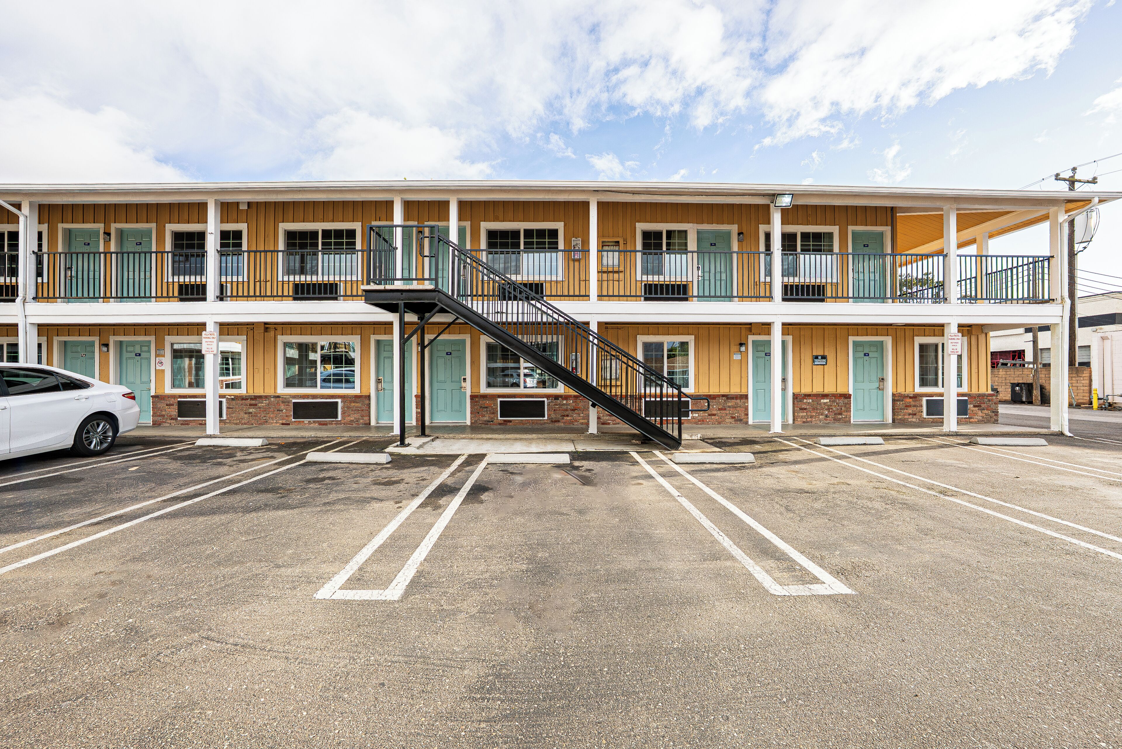 A motel with a two-story structure, a central staircase, and a parking lot.