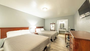 Une chambre d’hôtel avec deux lits « queen size », une commode en bois, un bureau et un téléviseur fixé au mur.