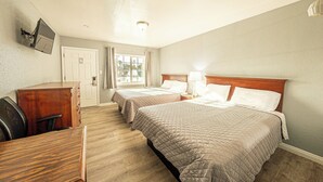 A hotel room with two beds, a desk, a chair, a TV mounted on the wall, and a window with curtains. - Villa Motel (Santa Maria)