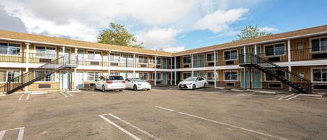 A motel with multiple floors, a parking lot, and several cars parked.