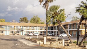 A motel with multiple rooms, a parking lot, and palm trees. - Villa Motel (Santa Maria)