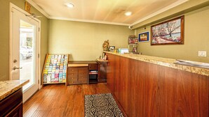 A reception area with a wooden counter, a bulletin board, and a door leading outside. - Villa Motel (Santa Maria)