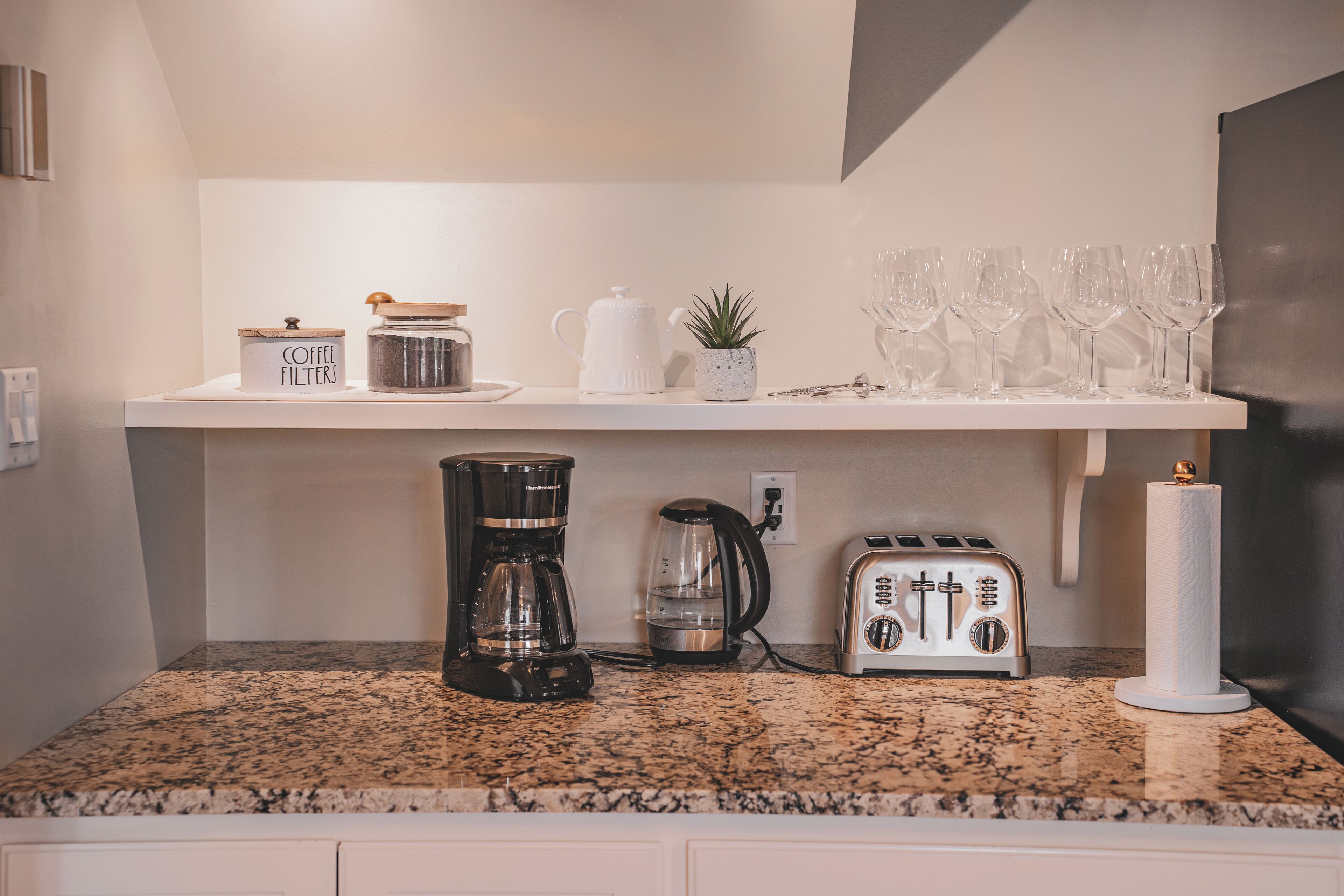 A kitchen counter with a coffee maker, toaster, and glassware.