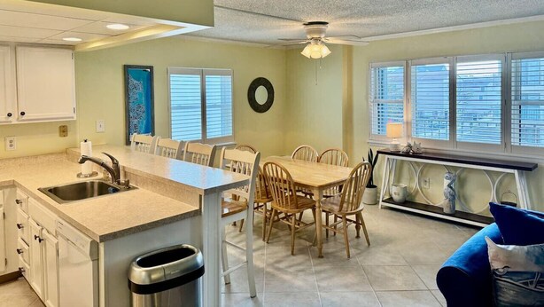 A kitchen with a dining area, a ceiling fan, and a view of the outside through large windows.