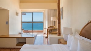 A hotel room with a large window offering a view of the sea, a bed, a desk, and a chair. - Tranquil Studio Hideaway in a Prime Location (San José del Cabo)
