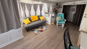 Ein Wohnzimmer mit einer Couch, einem Sessel, einer Lampe und einem kleinen Teppich.