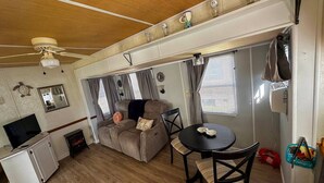 Ein kompakter Wohnbereich mit Sofa, Esstisch, Fernseher und Deckenventilator.