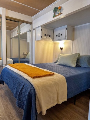 A bedroom with a bed, a nightstand, a mirror, and a wardrobe.