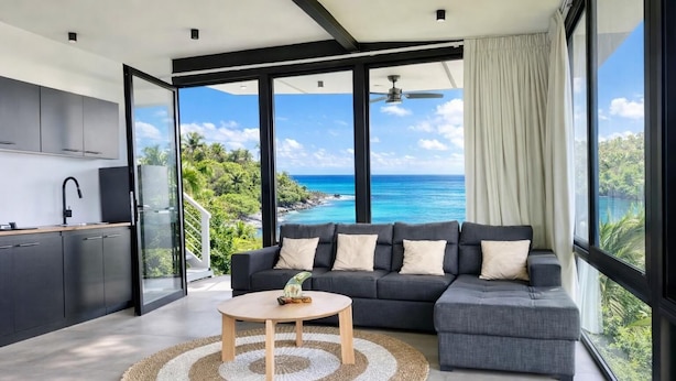 Ein modernes Wohnzimmer mit einem großen Fenster und Meer- und Grünblick.