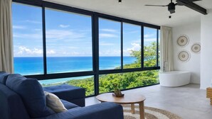 Un salon moderne doté d’une grande fenêtre offrant une vue imprenable sur l’océan.