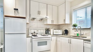 A modern kitchen with white cabinets, a built-in oven, a microwave, and a sink.