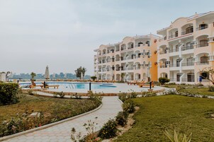 A hotel with a swimming pool, outdoor seating, and a well-maintained garden.
