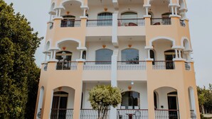 Un immeuble à plusieurs étages doté de balcons, d’une cour intérieure et d’un jardin bien entretenu.