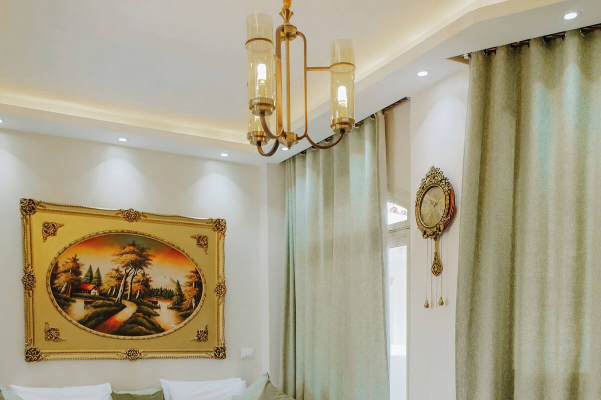 Ein Schlafzimmer mit einem großen Bett, einer Chandelier, einem Gemälde und einem gemusterten Teppich.