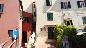 A narrow alleyway between buildings with a staircase leading up to a door.