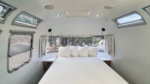 Quarto compacto com cama, janela e claraboia.