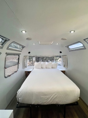 Ein gemĂŒtliches Schlafzimmer mit Bett, Fenster und Dachfenster.