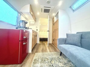 Ein kompaktes Wohnmobil-Interieur mit Küchenzeile, einem Bett und einer Sitzecke.
