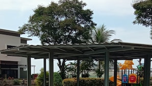 A covered outdoor area with a playground, a fountain, and a landscaped garden. - Apartemen Thamrin City 1 BR City View (Jakarta)