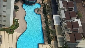 An aerial view of a swimming pool with a bridge, surrounded by residential buildings. - Apartemen Thamrin City 1 BR City View (Jakarta)
